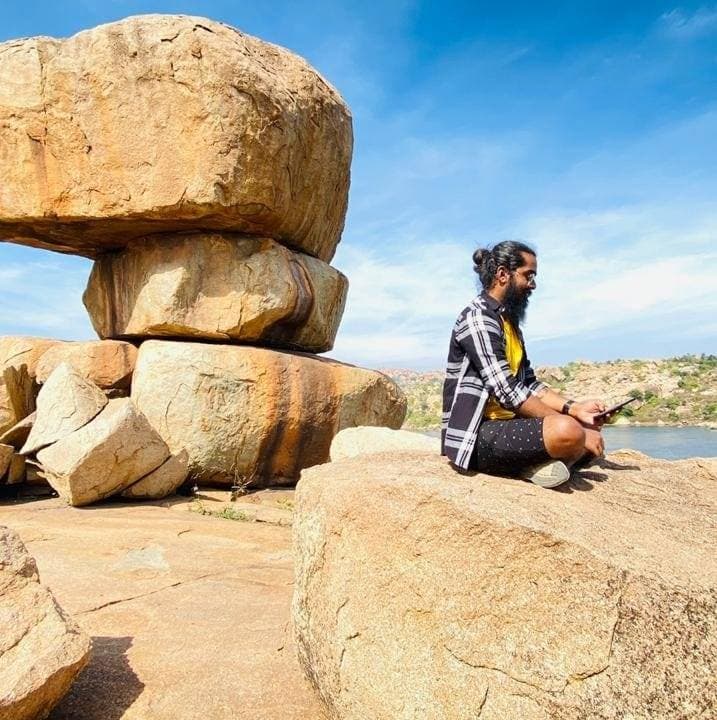 Girish watching his phone by Sanapur Lake, Hampi